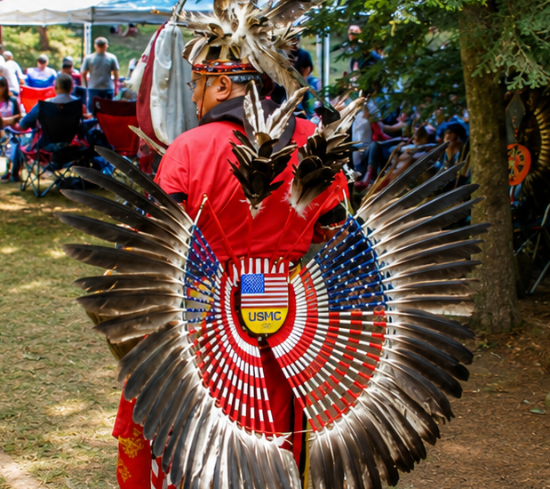 man in tribal wear with feathered backpiece